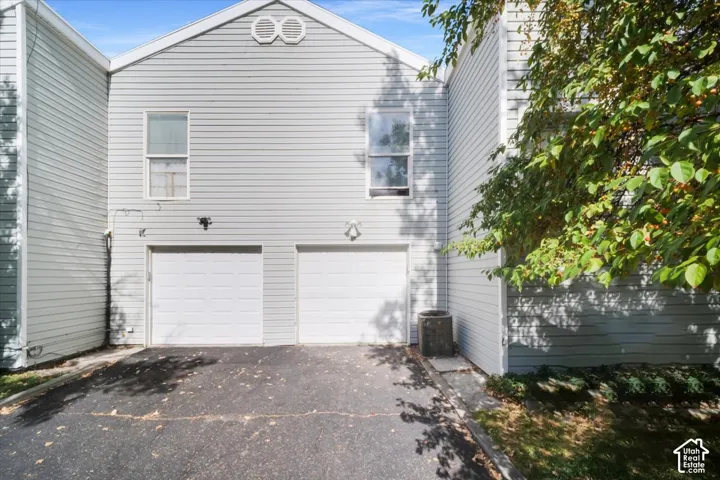 Light gray siding exterior with two garage doors and an asphalt driveway