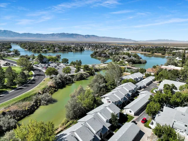 Multiple bodies of water, distant mountain range, residential properties, paved roadway, and mature trees