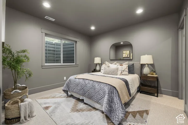 Recessed lighting, window with white trim, gray wall paint, light-colored carpeting, and a solid gray door