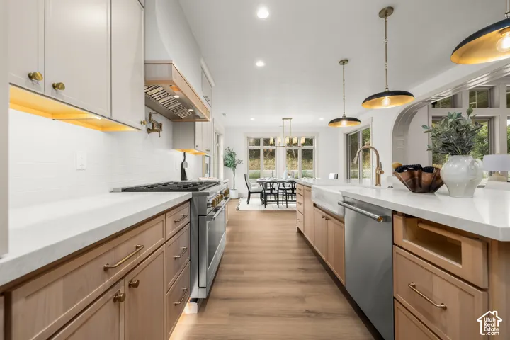 White countertops, wood-finish flooring, two-tone cabinetry, stainless steel appliances, and a farmhouse-style sink
