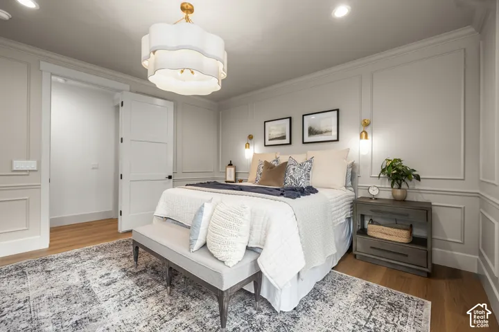 Hardwood-style flooring, decorative wall molding, recessed ceiling lighting, and a modern chandelier