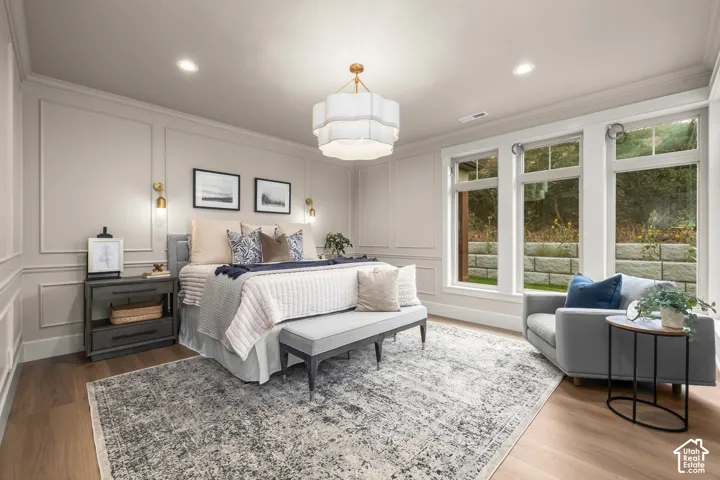 Wood-finish flooring with an area rug, recessed lighting, and a contemporary chandelier