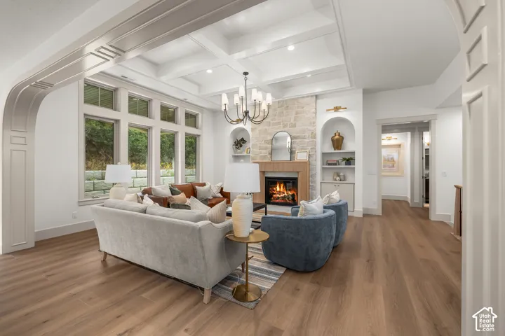 Coffered ceiling, wood-finish flooring, stone-clad fireplace, built-in shelving, and large windows