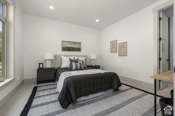 Recessed lighting illuminates this room featuring a window with a mountain backdrop, neutral wall tones, and light-toned carpet flooring
