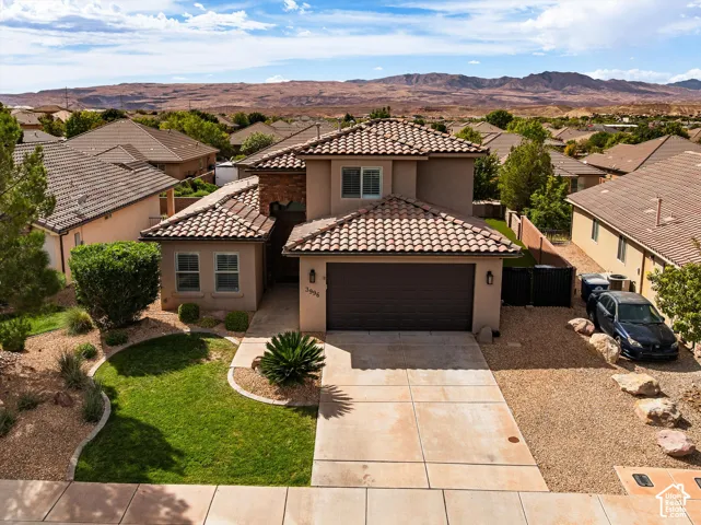 Mediterranean-style architecture with a tile roof, stucco exterior, and attached garage, tile roofing, private swimming pool, artificial turf, and mature landscaping