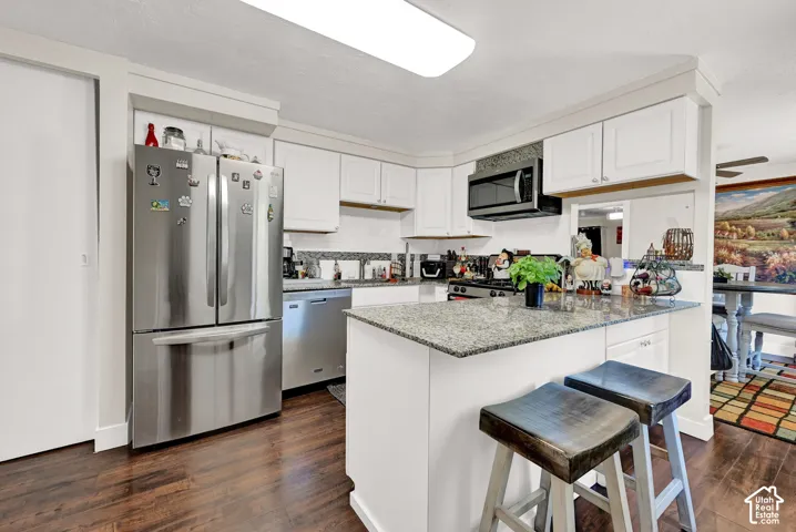 Kitchen featuring white cabinetry, a built-in microwave, a stainless steel refrigerator, and wood-finish flooring