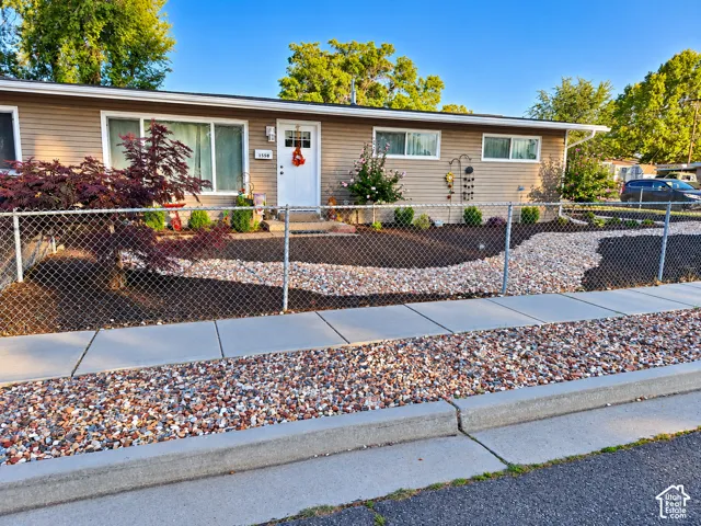 Low-maintenance front yard featuring river rock landscaping, concrete walkway, and mature shade trees