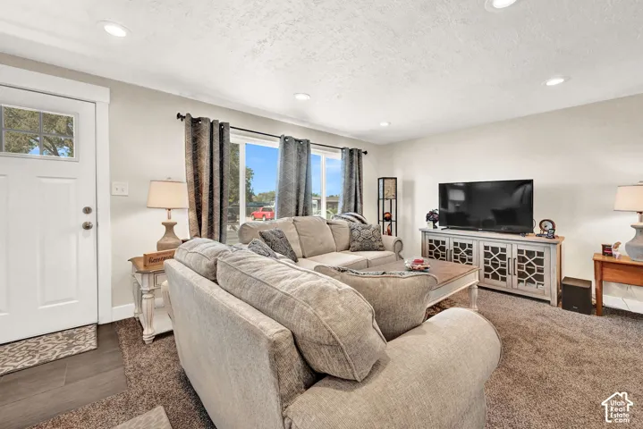 Recessed ceiling lighting, white interior door with decorative glass, wood-finish flooring, large windows, and a decorative console cabinet
