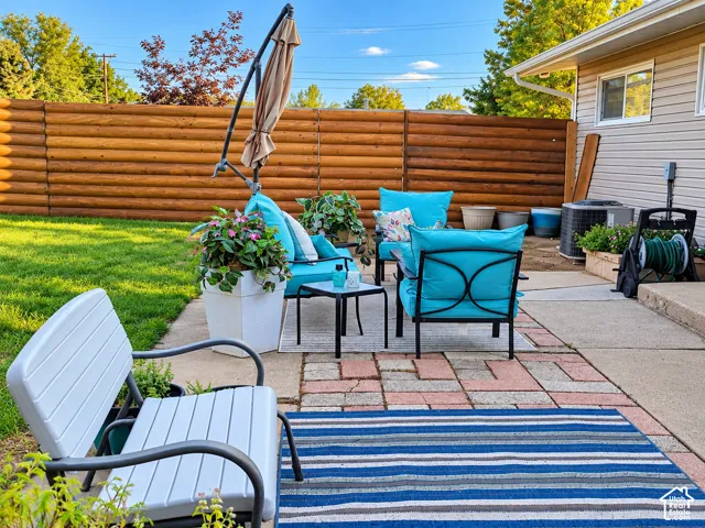 Expansive backyard featuring a log-style privacy fence, manicured lawn, and a multi-level patio with pavers and concrete