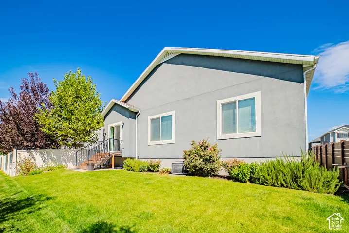 Expansive backyard with a manicured lawn, established landscaping, and a privacy fence