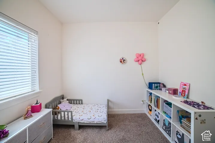 Carpeted flooring, white walls, and a window with blinds