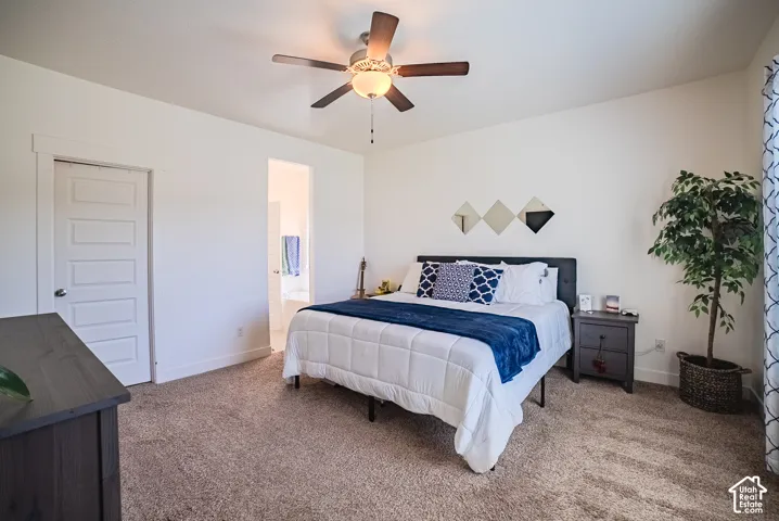 Carpeted room with white walls, a five-panel interior door, and a ceiling fan