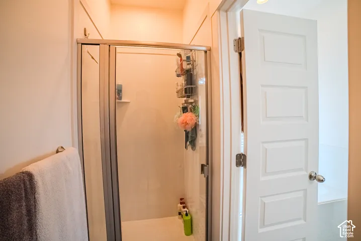 Glass-enclosed shower with a white surround and built-in shelving