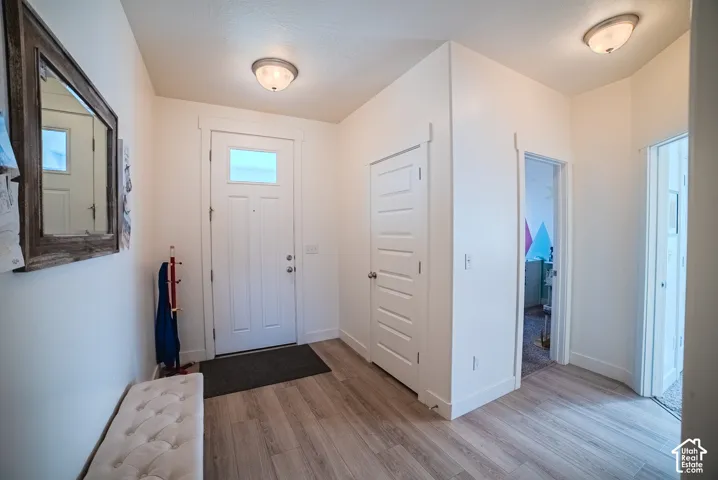 Entry area featuring wood-finish flooring, a white paneled entry door with frosted glass, and white walls