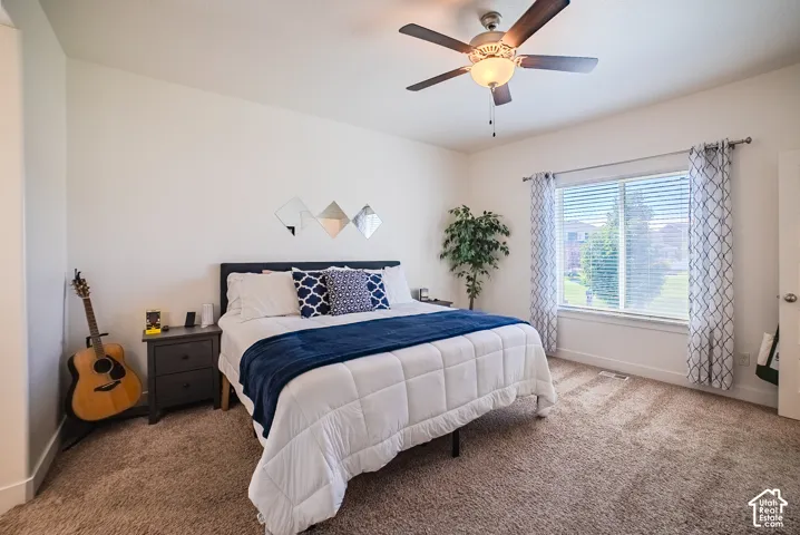 Spacious room featuring a ceiling fan with integrated lighting, a large window with blinds, and textured carpet flooring