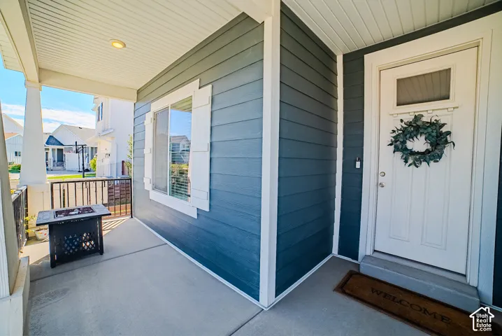 Covered porch with white columns, horizontal siding, white trim, and a built-in recessed light