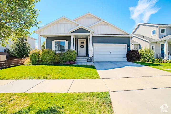 Contemporary exterior siding, attached garage, concrete driveway, front porch, and established landscaping