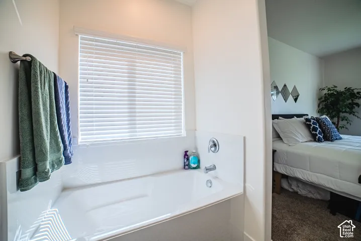 Built-in bathtub with a window, chrome fixtures, and a wall-mounted towel bar