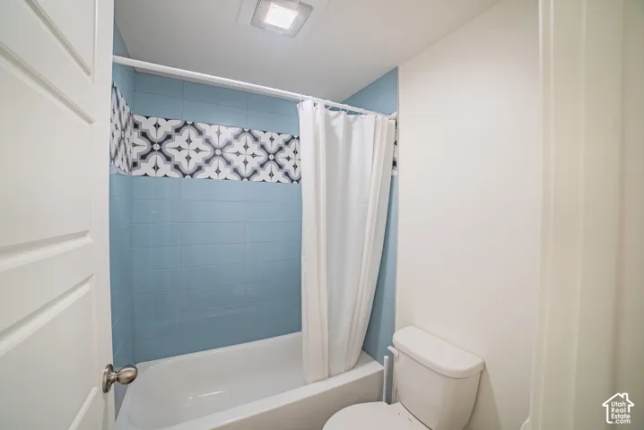 Bathtub with light blue subway tile surround and decorative patterned accent tile