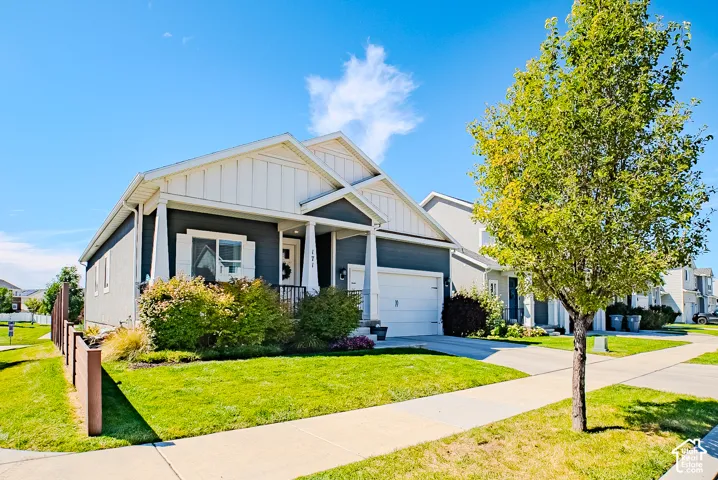 Single-story residence featuring a covered front porch, attached garage, and a manicured lawn