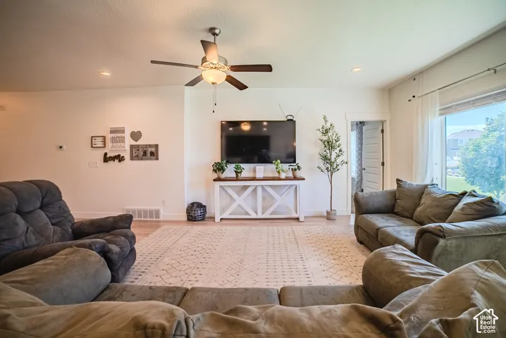Hardwood-style flooring, recessed lighting, ceiling fan with integrated light fixture, large window with natural light, and white interior doors