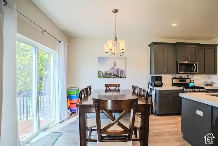 Dining area with wood-finish flooring, a contemporary chandelier, and a sliding glass door leading to an outdoor deck