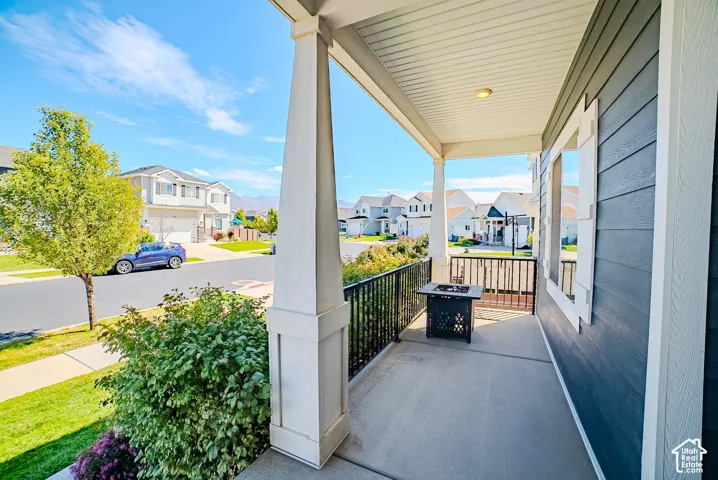 Covered concrete porch with white support columns, black metal railings, and a horizontal siding exterior