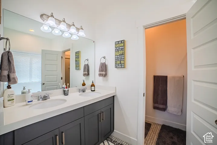 Dual vanity with integrated sinks, brushed nickel fixtures, a large wall-mounted mirror, and a multi-bulb light fixture