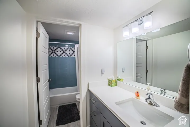 Bathroom featuring a vanity with an integrated sink, polished chrome faucet, and overhead illumination