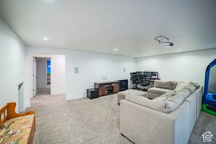 Recessed ceiling lighting, wall-mounted speakers, ceiling-mounted projector, and neutral carpeting