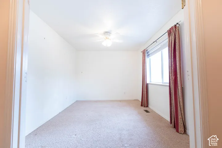 Recessed window with decorative curtain rods, ceiling-mounted fan fixture, and carpeted flooring