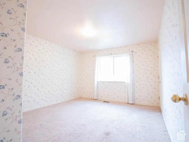 Wall-to-wall carpeting, window with sheer treatments, overhead lighting fixture, and a white door with brass hardware