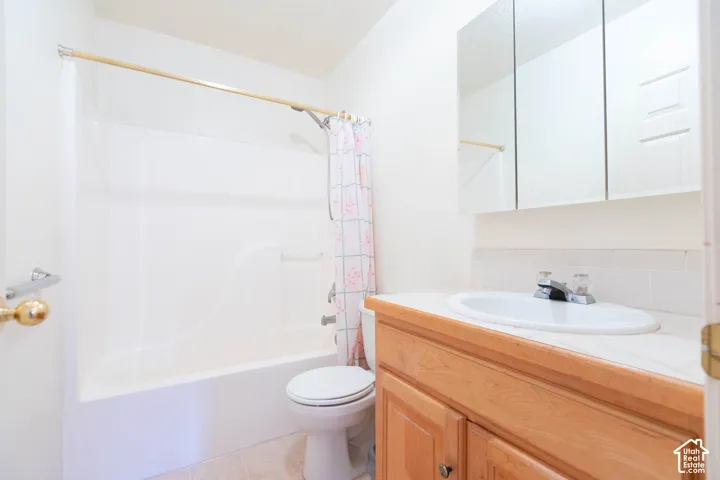 Bathroom featuring a white integrated tub/shower unit, a wood-finish vanity with an integrated sink, and a mirrored medicine cabinet