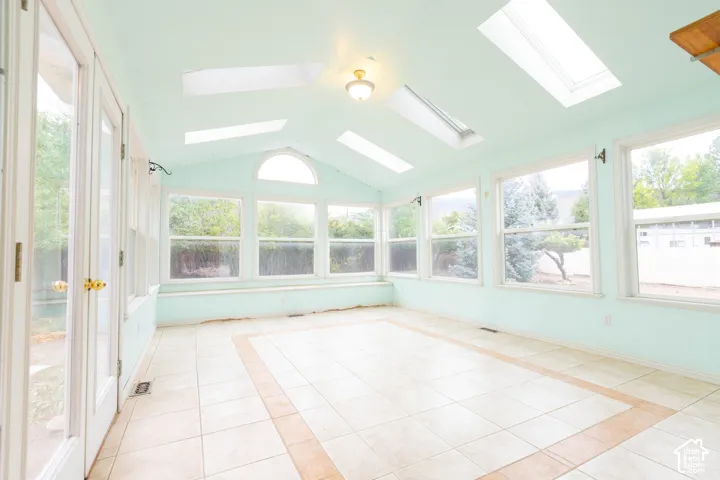 Room featuring an arched window, multiple skylights, and tiled flooring with an accent border
