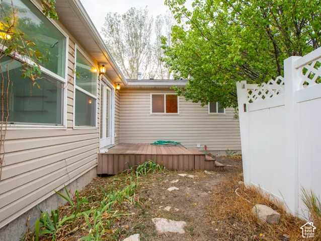 Beige siding exterior with multiple windows, leading to a raised composite deck