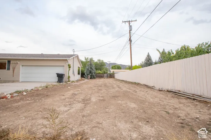 Exterior siding, garage with attached door, concrete driveway, and privacy fence
