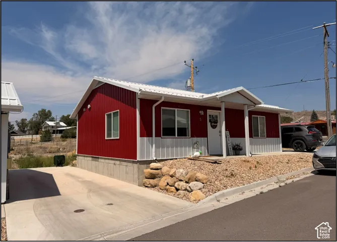 Red and white corrugated metal siding, white metal roof, white frame windows, covered front entrance, and gravel landscaping