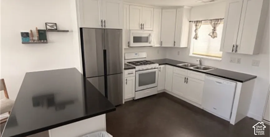 White cabinetry with black hardware, dark countertops, and stainless steel appliances