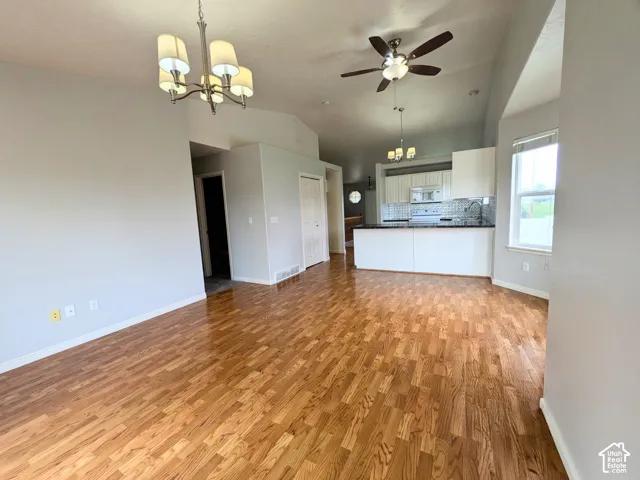 Open concept living area featuring wood-finish flooring, vaulted ceilings, and a ceiling fan