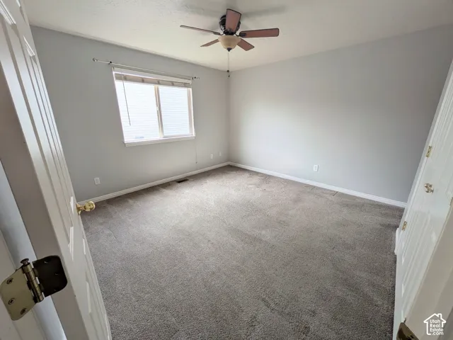Neutral-toned carpeting, light gray walls, and a ceiling fan with integrated lighting