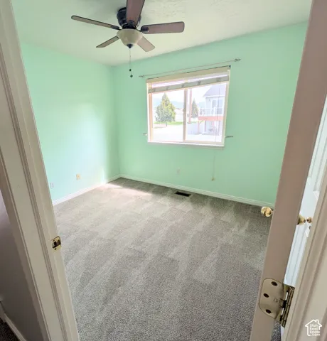 Carpeted room with a ceiling fan, a window with horizontal blinds, and light-colored walls