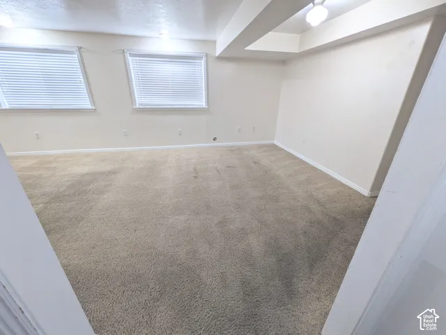 Spacious carpeted room with neutral wall finishes, recessed ceiling lighting, and dual casement windows providing natural illumination