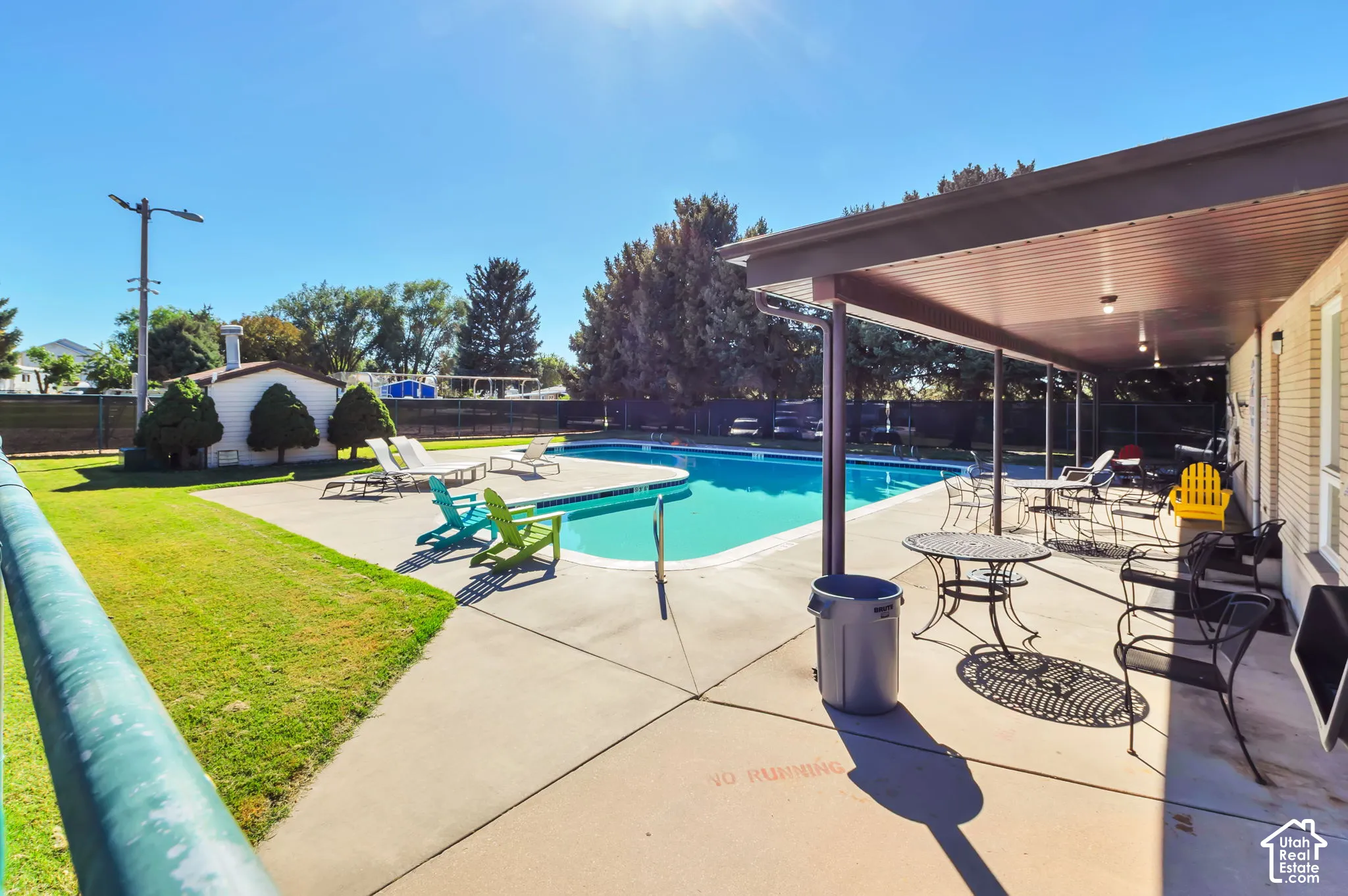 Outdoor swimming pool with a concrete surround, an expansive covered patio, and a grass lawn area