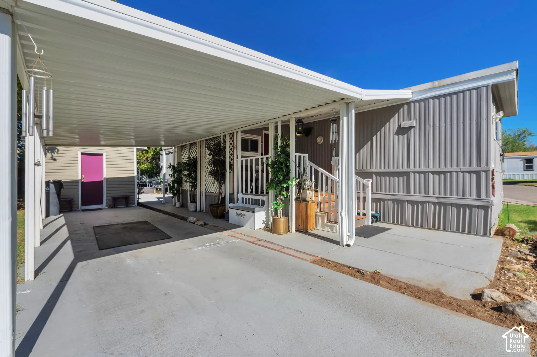 Full-length covered carport, covered front entry, exterior siding, porch with white railing, and exterior lighting