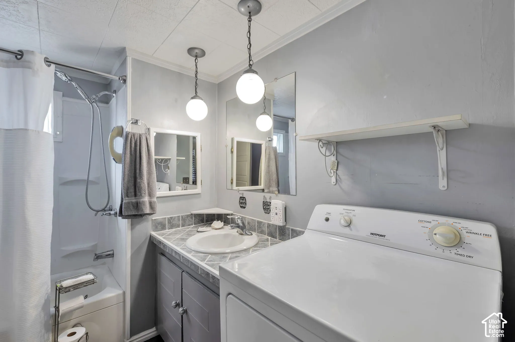Full bathroom featuring a shower-tub combination, vanity with countertop, and integrated laundry appliances