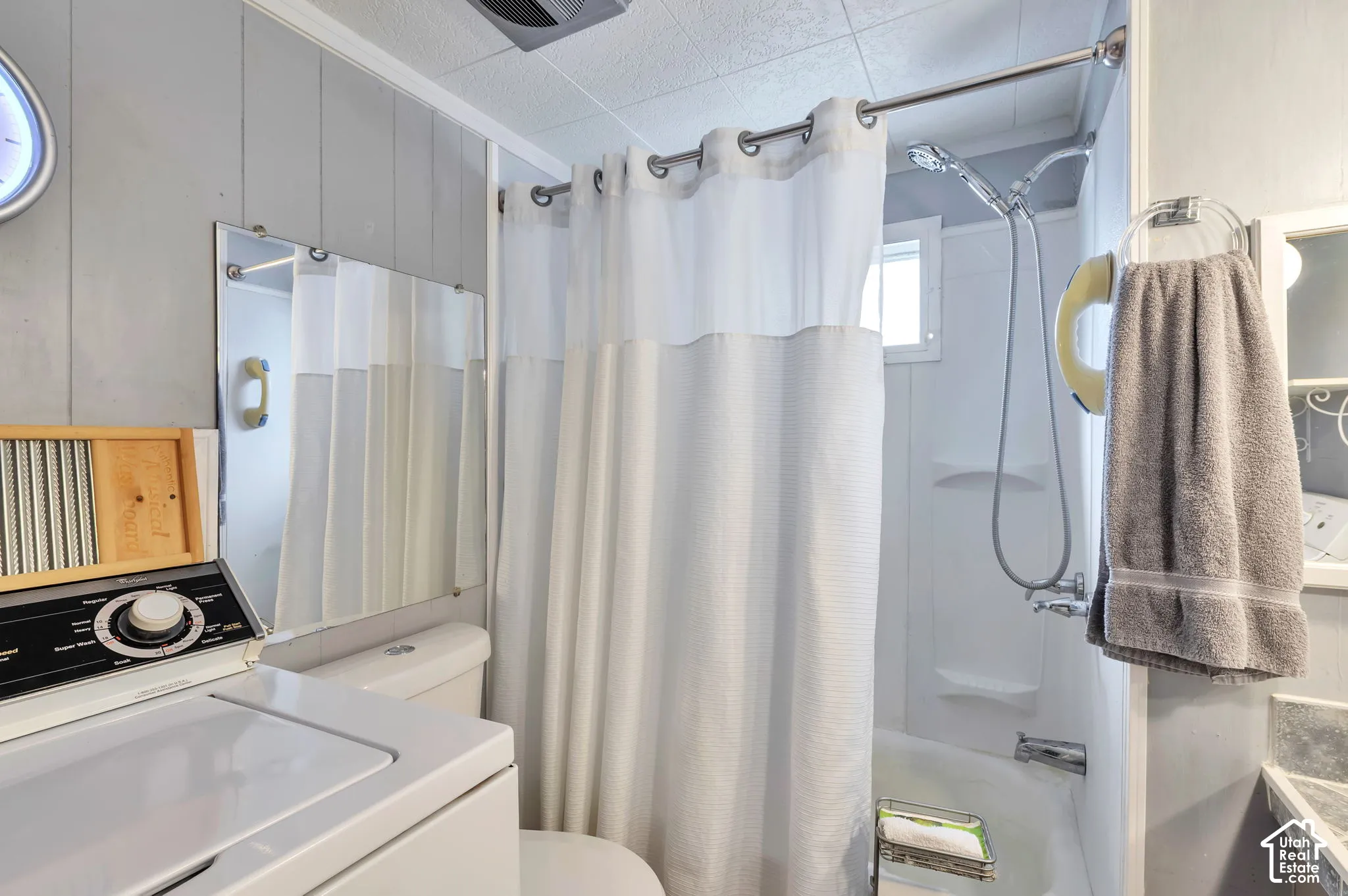 Shower-over-tub combination with a wall-mounted showerhead, paneling on walls, and a built-in window