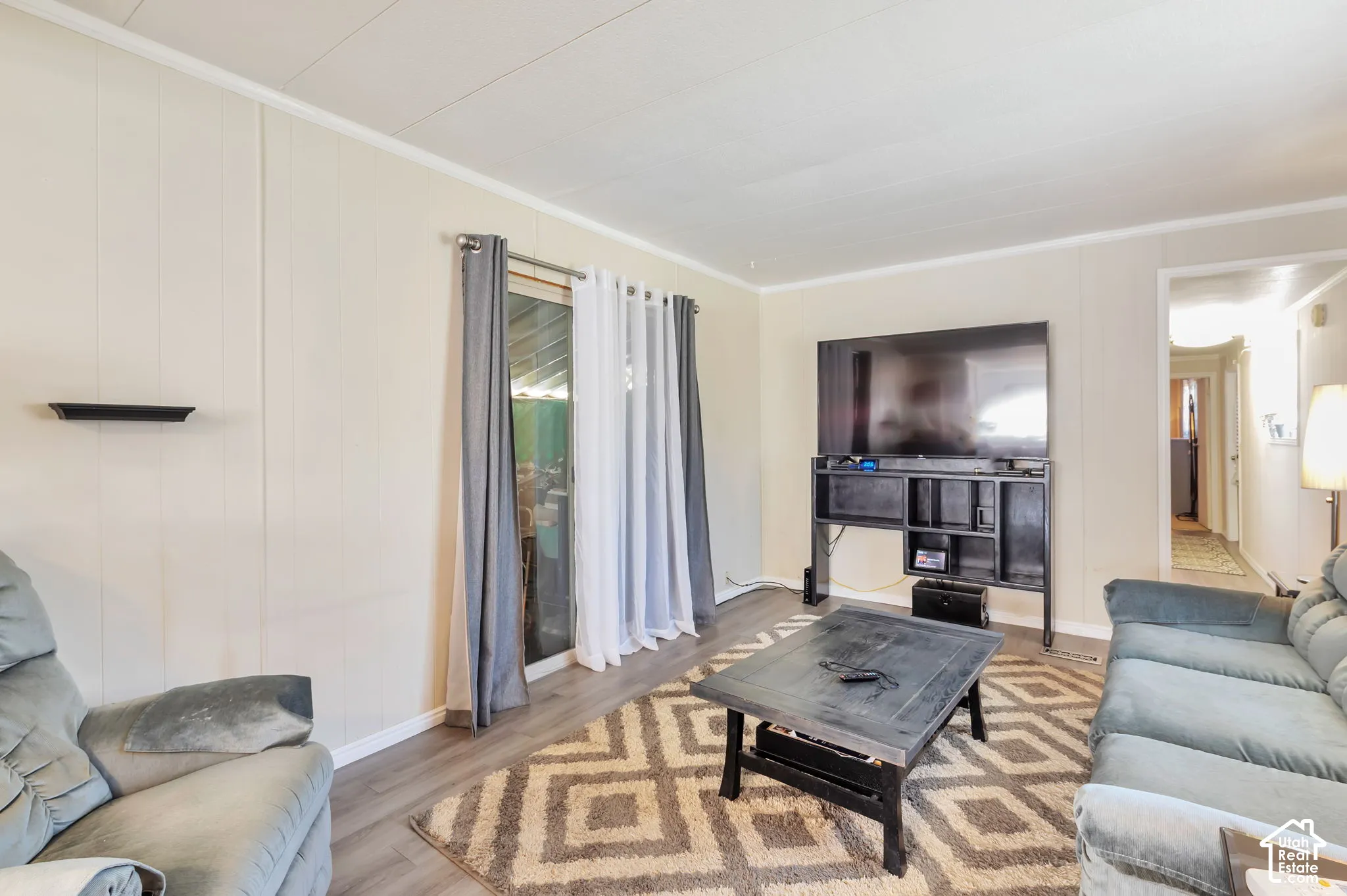 Living area featuring wood-finish flooring, vertical paneling, and a sliding glass door