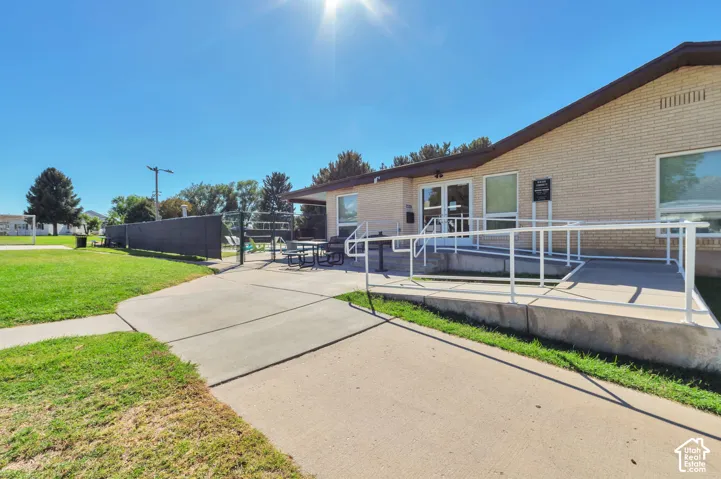 Brick exterior with a covered entry, concrete walkway, and a white handrail
