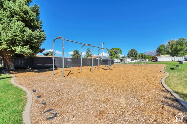 Park area featuring a swing set, wood chip surfacing, and a concrete border