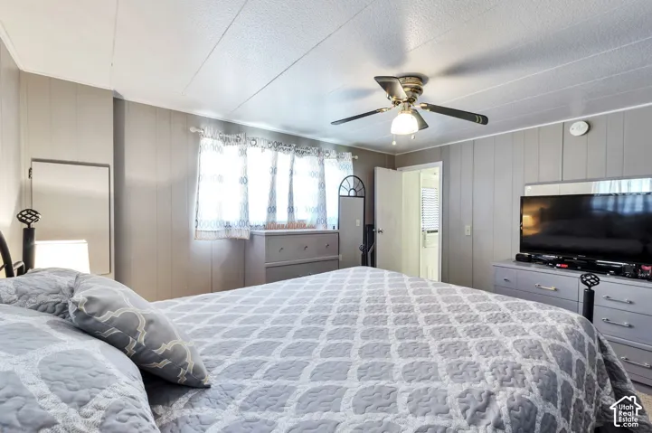 Recessed lighting with a ceiling fan, wall-mounted mirror, and paneled walls